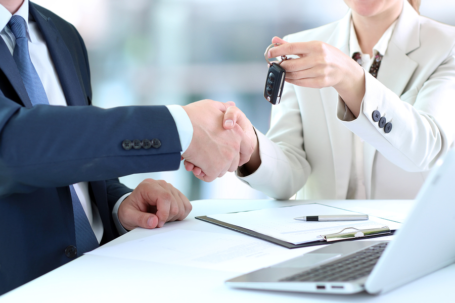 salesperson handing customer keys to new car